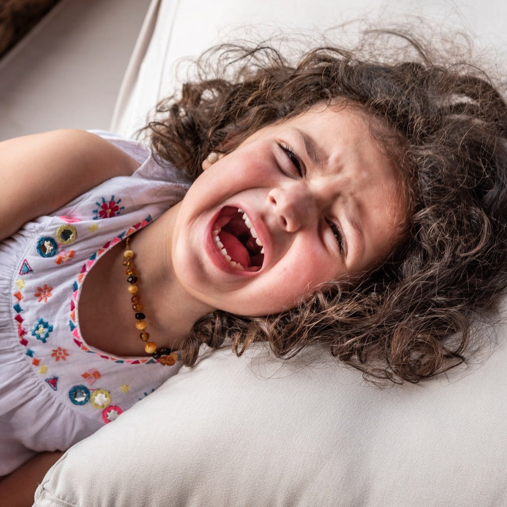Petite fille en pleurs pendant le brossage de ses cheveux bouclés